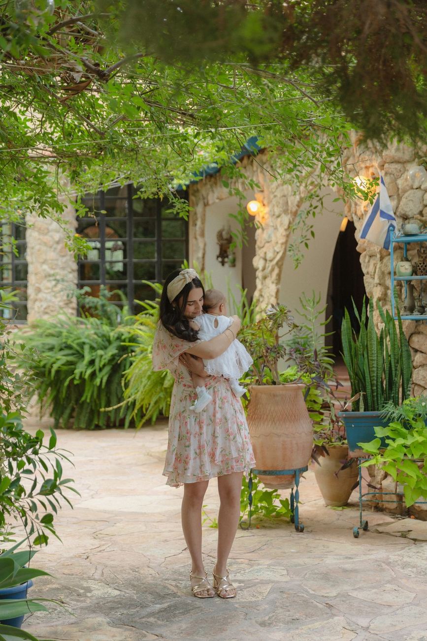 אמא מחבקת את התינוקת בחצר